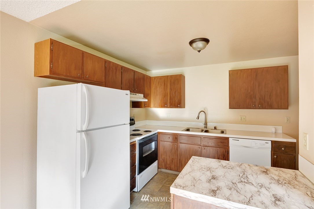 3910 Mason Loop Road Tacoma, WA 98409 - Photo 4 of 9 a kitchen with a sink a refrigerator and cabinets