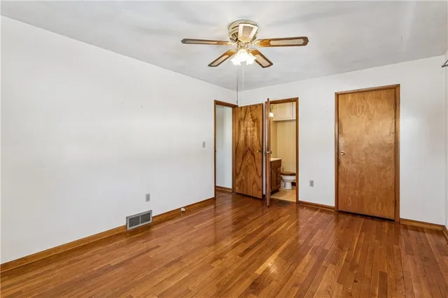 an empty room with wooden floor and ceiling fan