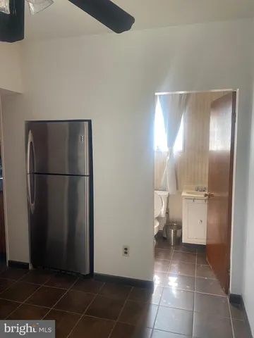 a view of a refrigerator in kitchen and an empty room with wooden floor windows