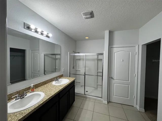 a spacious bathroom with a granite countertop double vanity sink a mirror and glass door