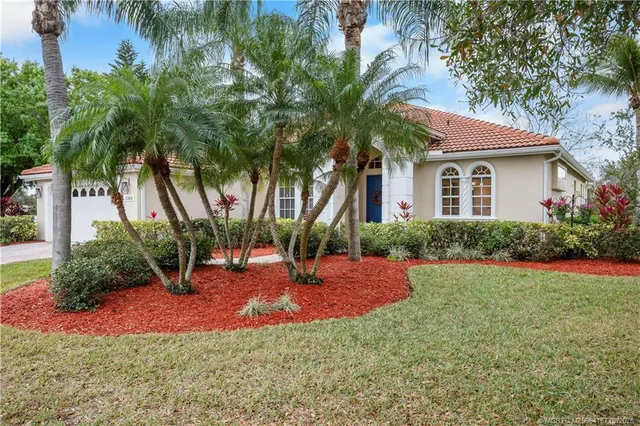 a view of a house with a yard and palm trees