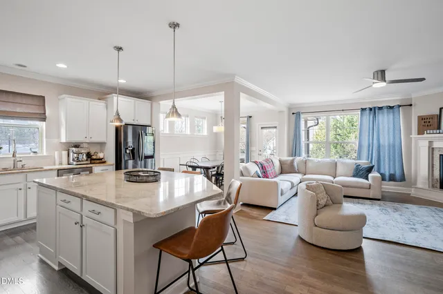 a kitchen with stainless steel appliances granite countertop a dining table chairs refrigerator and microwave