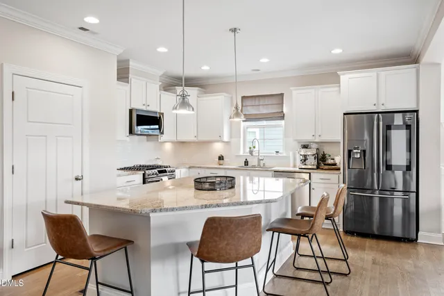 a kitchen with a stove a refrigerator and chairs