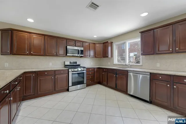 a kitchen with a sink a stove top oven and wooden cabinets