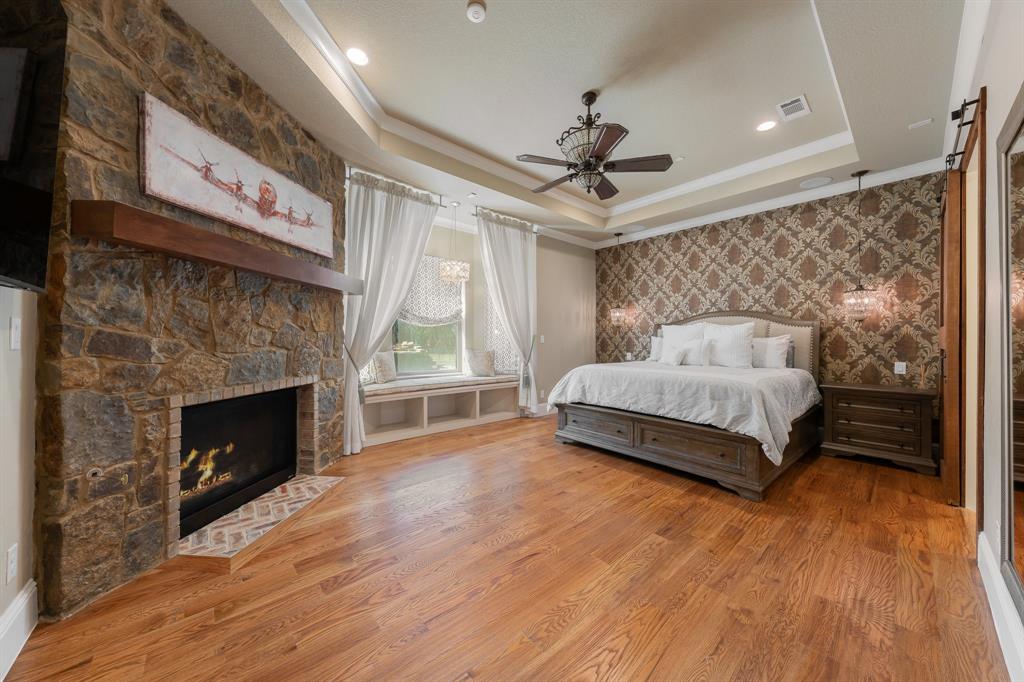 594 Turner Warnell Road Mansfield, TX 76063 - Photo 18 of 38 Primary bedroom featuring a tray ceiling, crown molding, hardwood floors, a fireplace, and ceiling fan