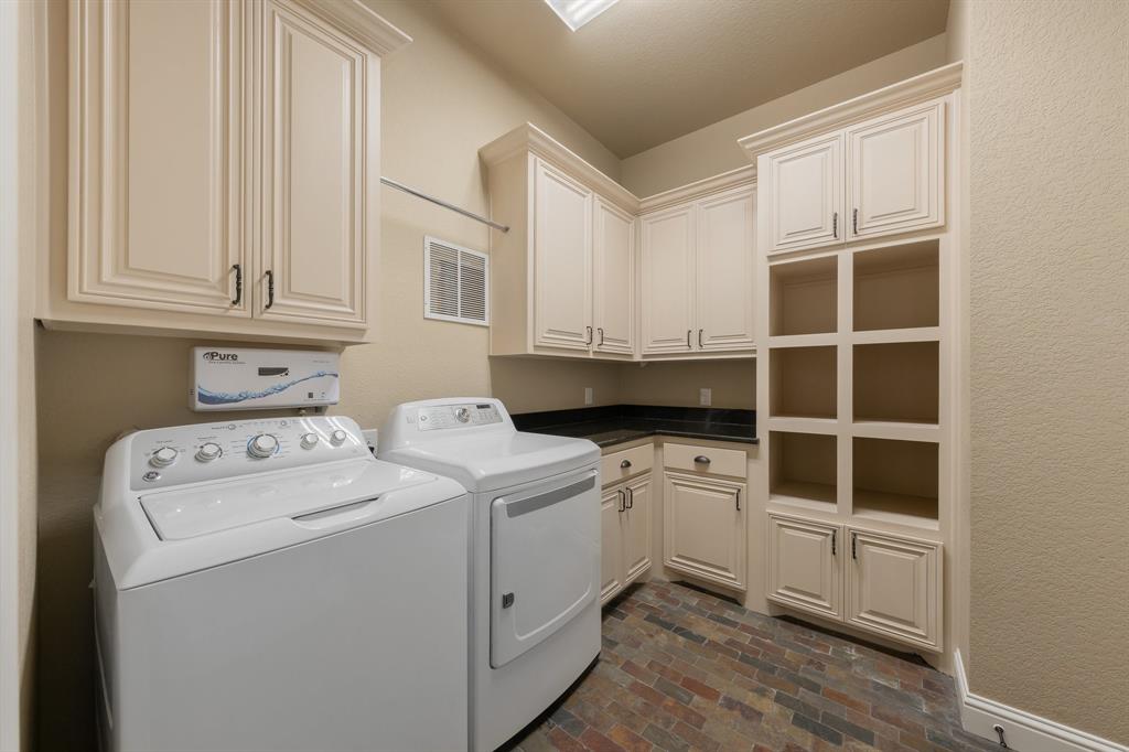 594 Turner Warnell Road Mansfield, TX 76063 - Photo 22 of 38 Washroom with brick floors, washer and dryer, a textured wall, and cabinet space