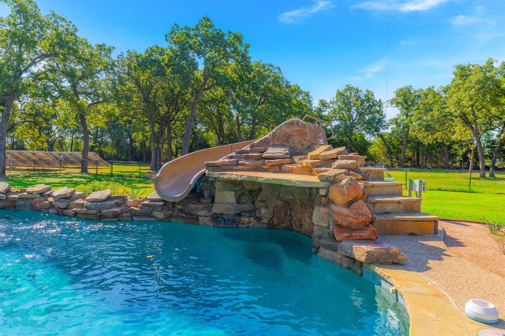 594 Turner Warnell Road Mansfield, TX 76063 - Photo 34 of 38 Swimming pool featuring view of scattered trees and a water slide and grotto
