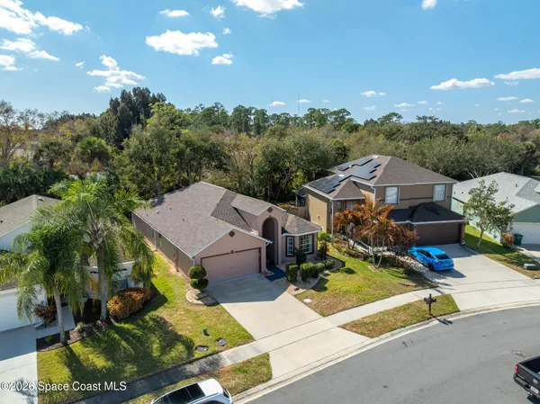 a view of a house with a big yard plants and large tree