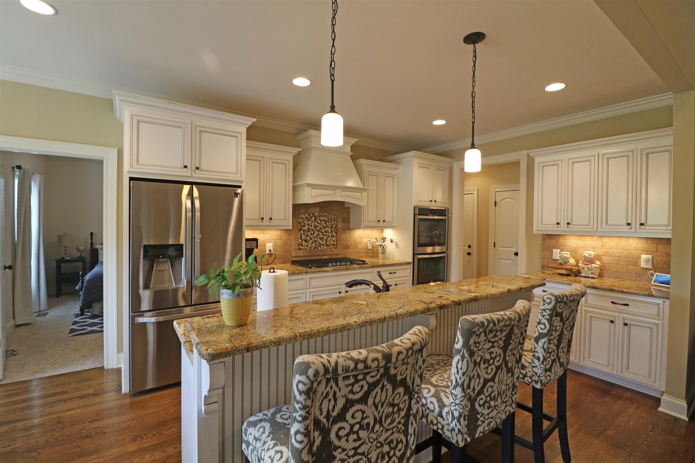 1235 Mires Road Mount Juliet, TN 37122 - Photo 9 of 30 Spacious 11x13 Kitchen design w/ upgraded custom cabinets, tile backsplash, under-cabinet lighting, raised breakfast bar with pendant lighting, crown molding, recessed lighting, gas cook-top, double ovens, microwave drawer, and hardwood flooring.