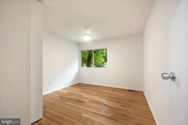 a view of an empty room with a window and wooden floor