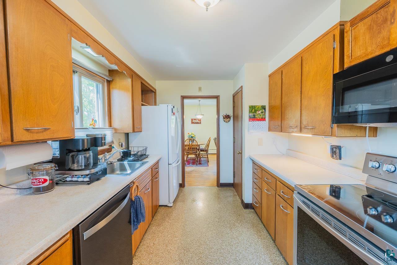101 2nd Avenue North Biwabik, MN 55708 - Photo 6 of 44 Galley kitchen featuring light wood cabinetry, light countertops, and a full suite of appliances including a range, microwave, and dishwasher