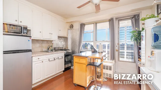 a kitchen with stainless steel appliances granite countertop a refrigerator a stove a sink and white cabinets with wooden floor