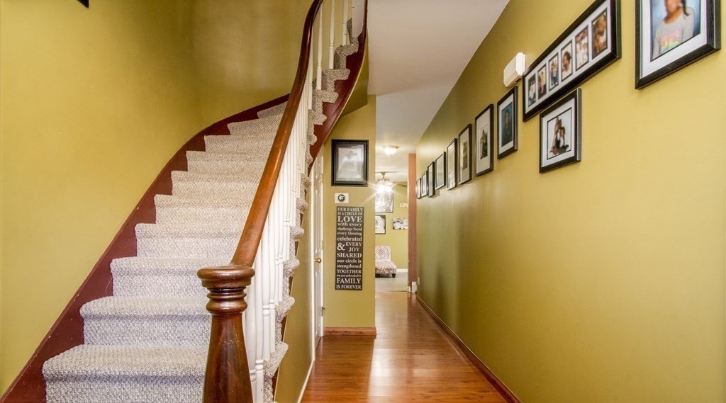 a view of staircase with lots of frames on wall and wooden floor