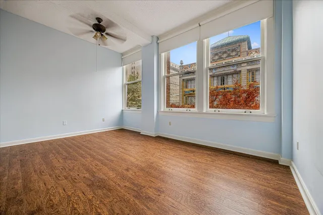 a view of an empty room with a window and wooden floor