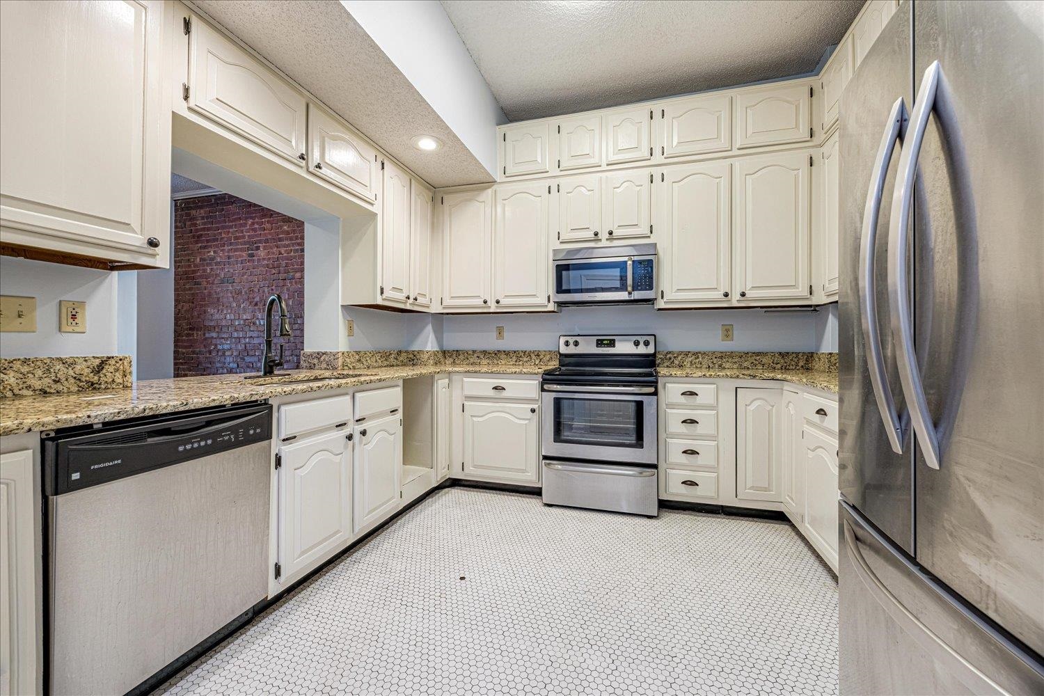 10 North Main Street, Unit 301 Memphis, TN 38103 - Photo 23 of 31 a kitchen with granite countertop white cabinets and stainless steel appliances