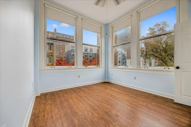 a view of an empty room with wooden floor and a window