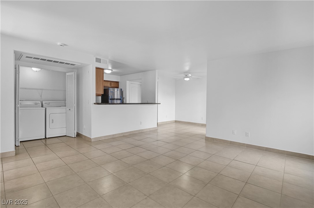 9325 West Desert Inn Road, Unit 177 Las Vegas, NV 89117 - Photo 2 of 13 Unfurnished living room featuring washing machine and dryer, light tile patterned floors, and a ceiling fan