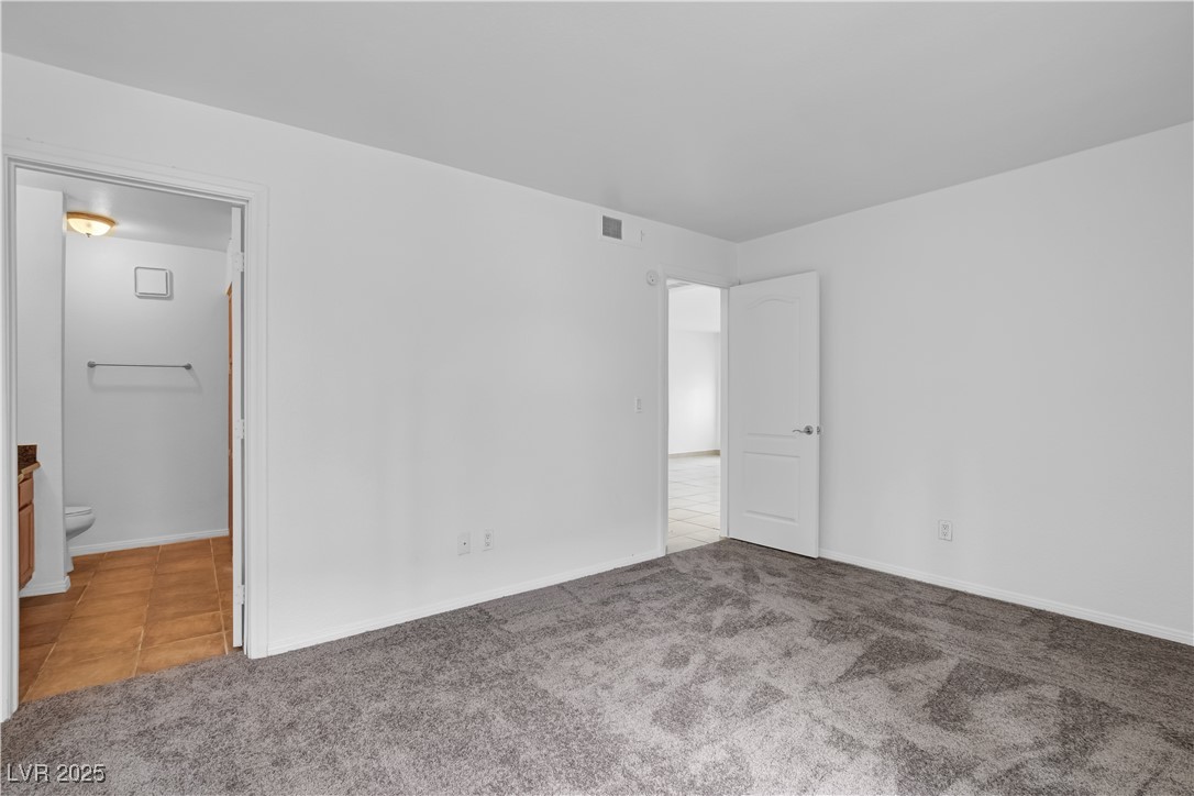 9325 West Desert Inn Road, Unit 177 Las Vegas, NV 89117 - Photo 8 of 13 Unfurnished bedroom featuring carpet floors, tile patterned floors, and ensuite bathroom
