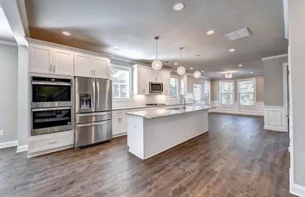 a large kitchen with granite countertop a large counter top stainless steel appliances and cabinets