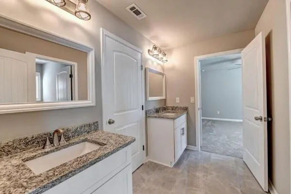 a bathroom with a granite countertop sink double vanity and a mirror