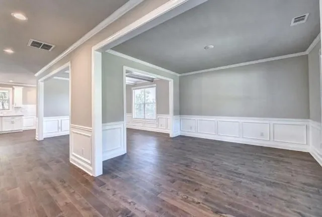 a view of an empty room with wooden floor fireplace and a window