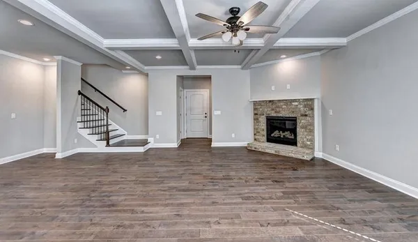 a view of an empty room with wooden floor fireplace and a window