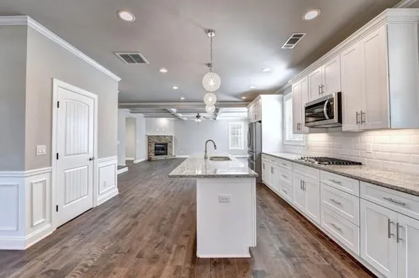 a large kitchen with granite countertop a large center island a sink stainless steel appliances and cabinets