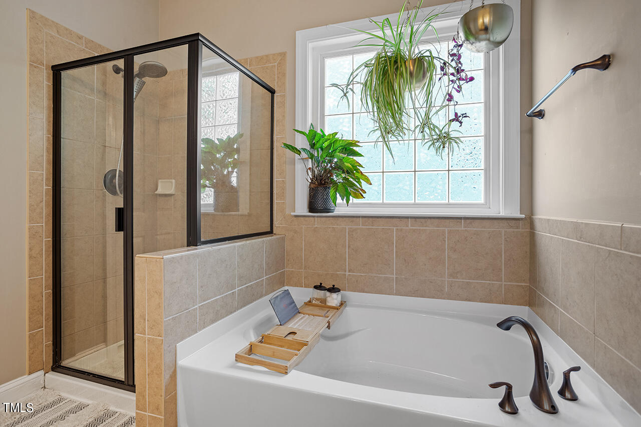 920 Chapanoke Road Raleigh, NC 27603 - Photo 20 of 47 a bathroom with a bathtub a window and a shower