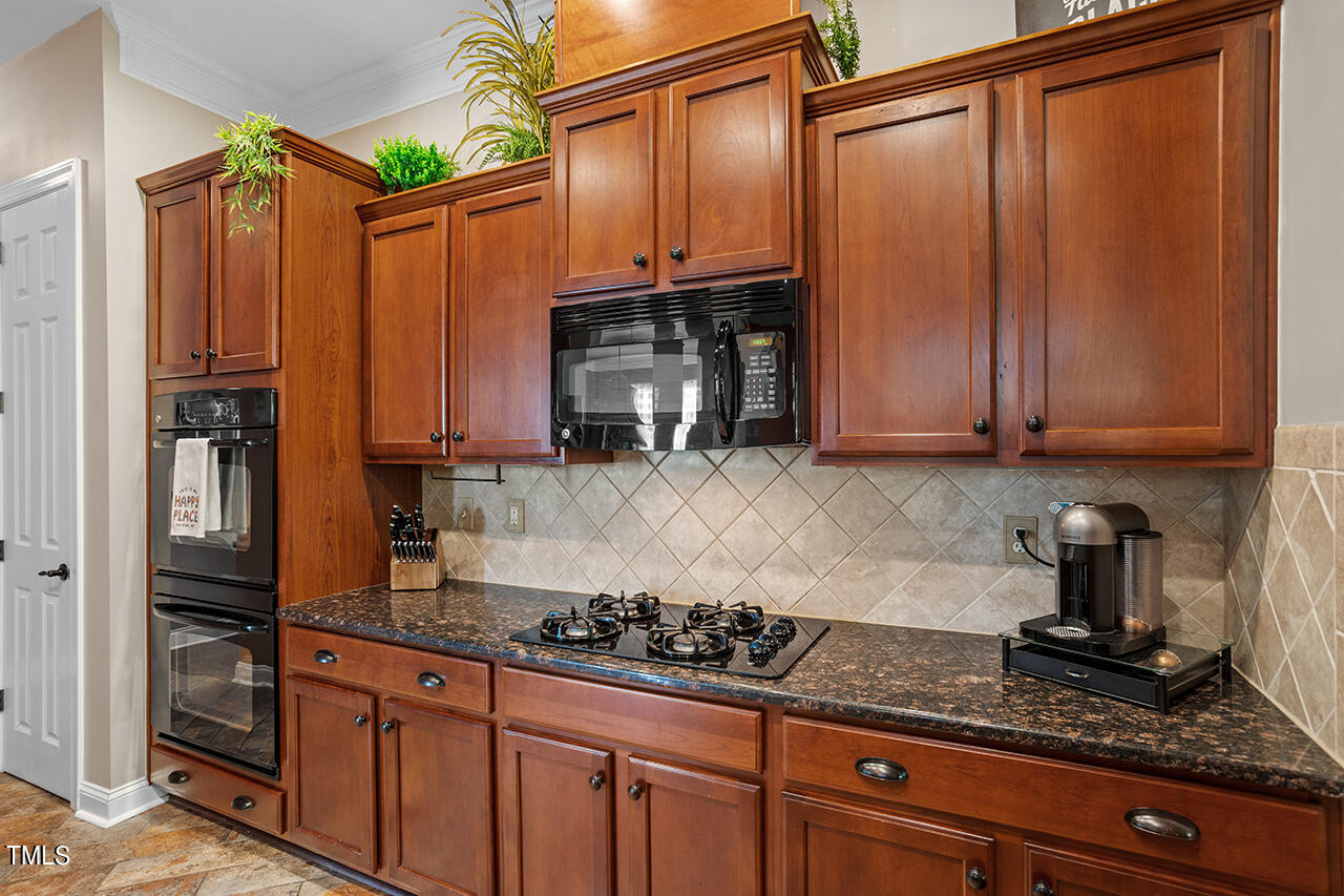920 Chapanoke Road Raleigh, NC 27603 - Photo 5 of 47 a kitchen with stainless steel appliances granite countertop a refrigerator a stove and a sink with wooden cabinets