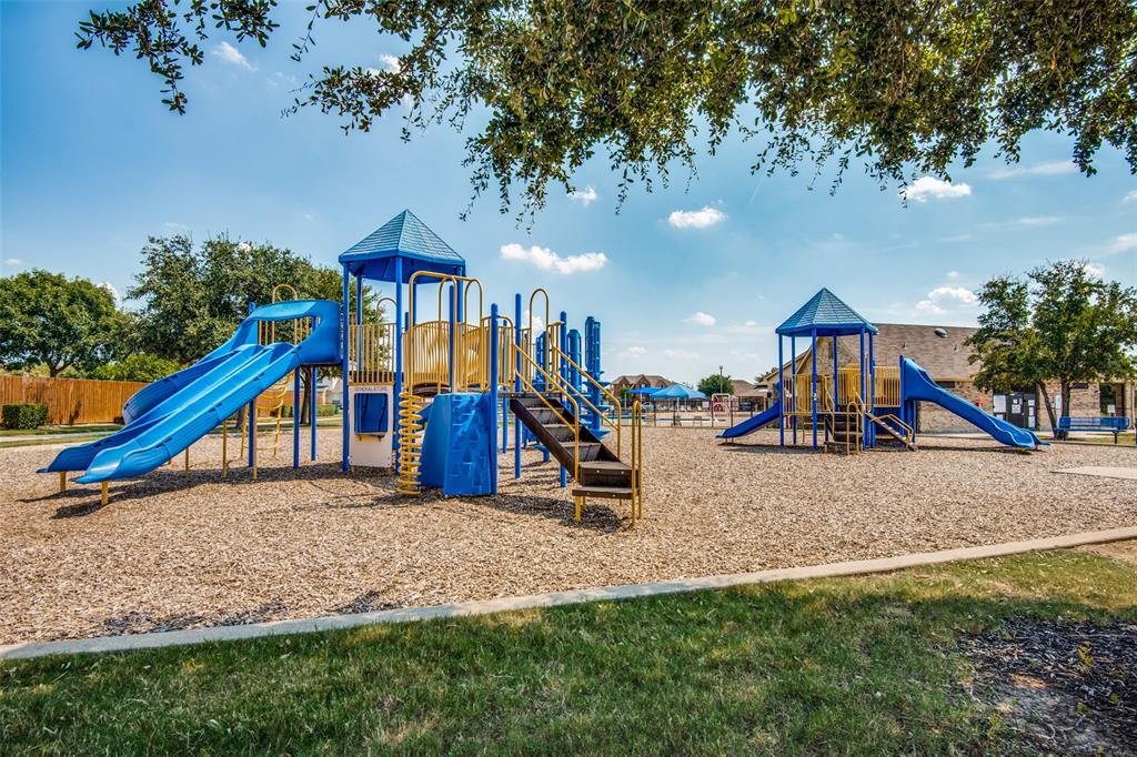 1257 Barrel Run Fort Worth, TX 76052 - Photo 24 of 26 Community playground featuring multiple blue and yellow play structures, slides, and climbing elements set on a wood chip surface
