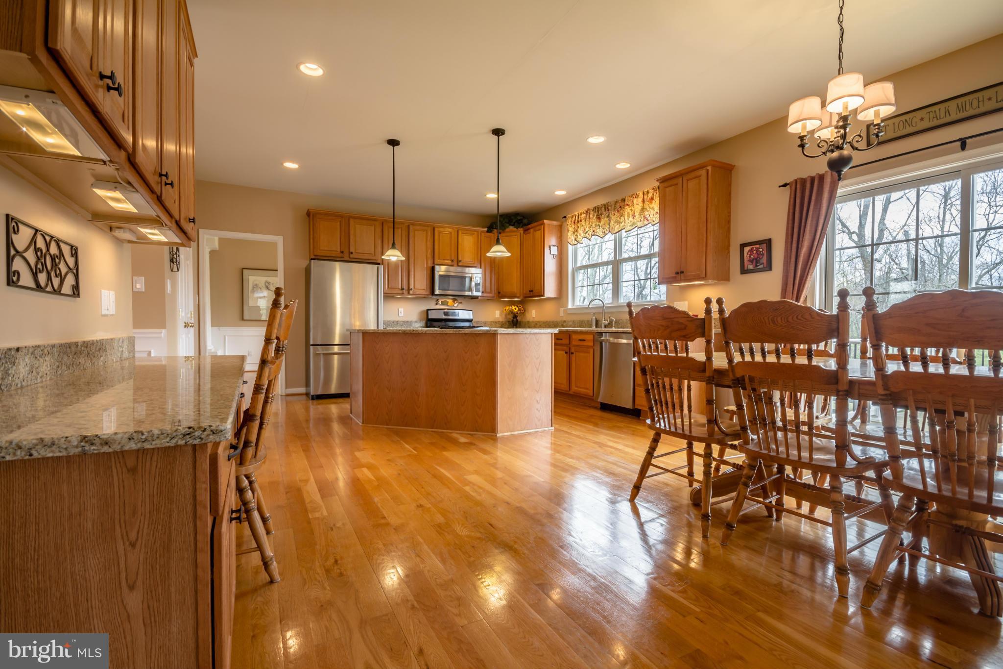 171 Wright Road Winchester, VA 22603 - Photo 5 of 30 a kitchen with stainless steel appliances granite countertop a stove top oven a refrigerator a dining table and chairs with wooden floor