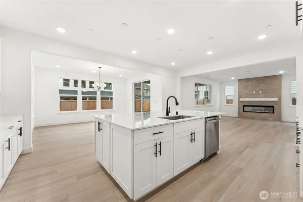 a large white kitchen with a lot of cabinets and wooden floor