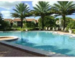 a view of swimming pool with a yard and palm trees