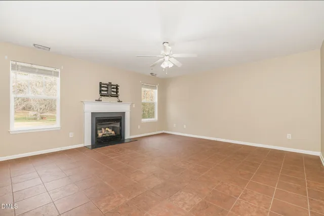 an empty room with windows and fireplace