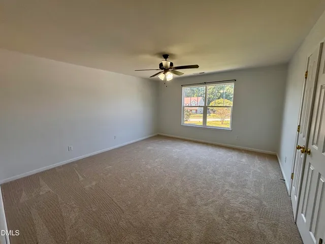 an empty room with windows and fan