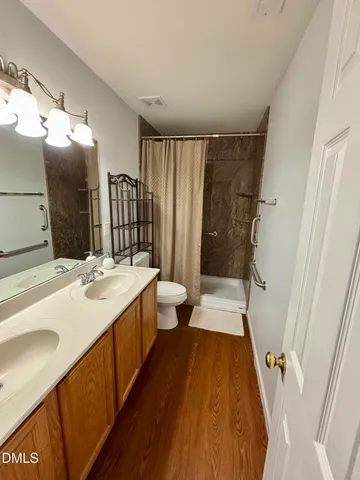 a bathroom with a double vanity sink and mirror with toilet
