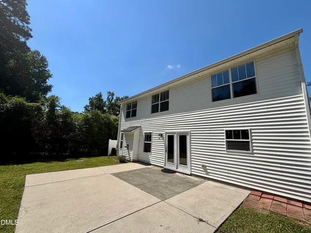 a view of house with backyard and trees in the background