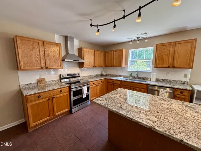 a kitchen with stainless steel appliances granite countertop a sink stove window and refrigerator