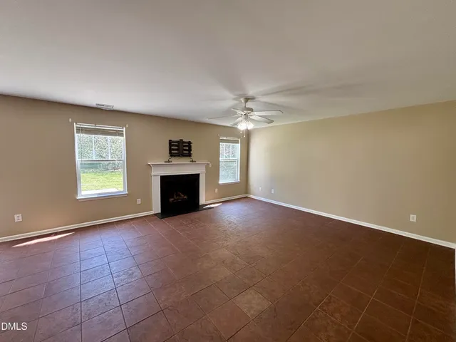 an empty room with windows and fireplace