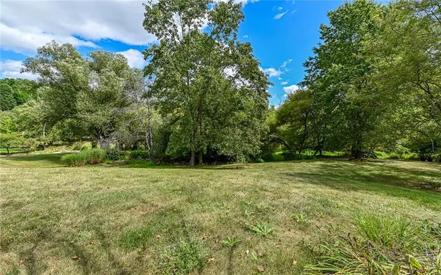 a view of a big house with a big yard and large trees