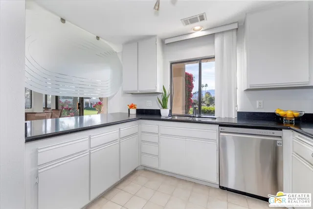 a kitchen with white cabinets and window