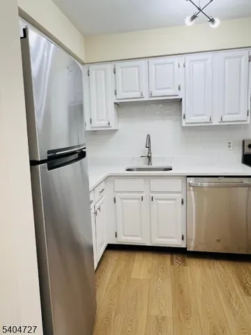 a kitchen with white cabinets and refrigerator