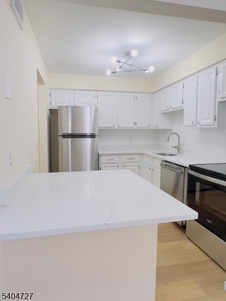 27 Alexandria Way, Unit 27 Bernards, NJ 07920 - Photo 9 of 19 a kitchen with a refrigerator a sink and white cabinets