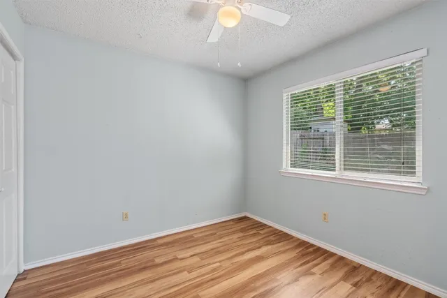 a view of empty room with wooden floor and fan