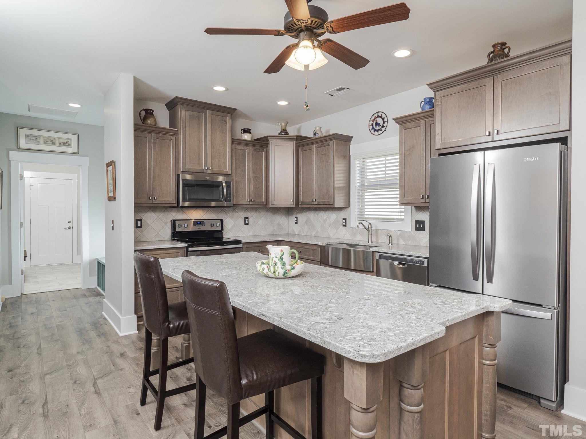 137 Bella Square Smithfield, NC 27577 - Photo 5 of 29 a kitchen with stainless steel appliances granite countertop a kitchen island a stove a refrigerator a sink a table and chairs