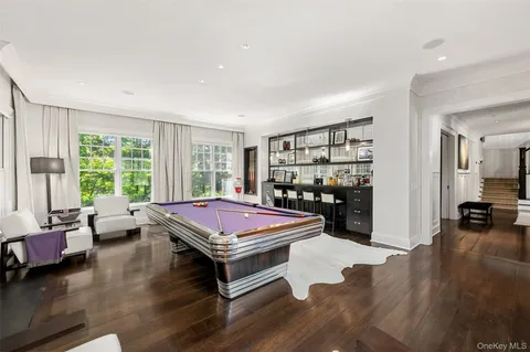 a room with furniture pool table wooden floor and windows