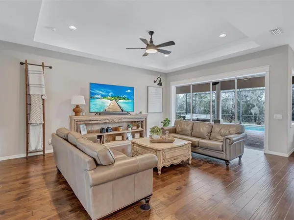 a living room with furniture kitchen view and a wooden floor