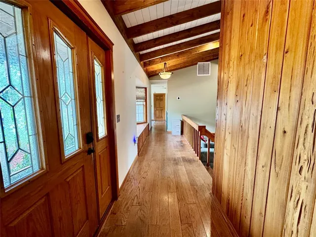 a view of a hallway with wooden floor and stairs