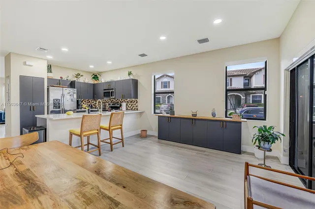 a kitchen with stainless steel appliances kitchen island granite countertop a refrigerator a stove and a wooden floors