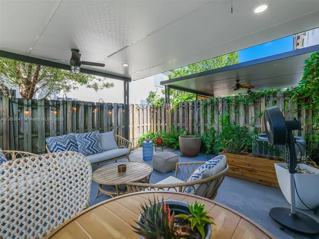 a view of a patio with couches chairs potted plants and floor to ceiling window